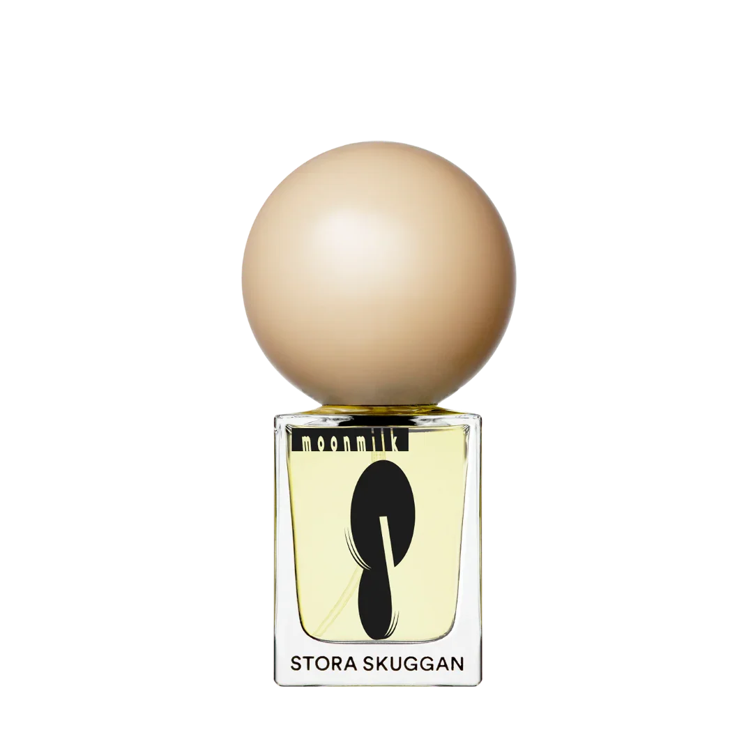 Parfümflakon "Moonmilk" von Stora Skuggan mit runder, beigefarbener Kappe und transparentem Glas, schwarzes Logo.