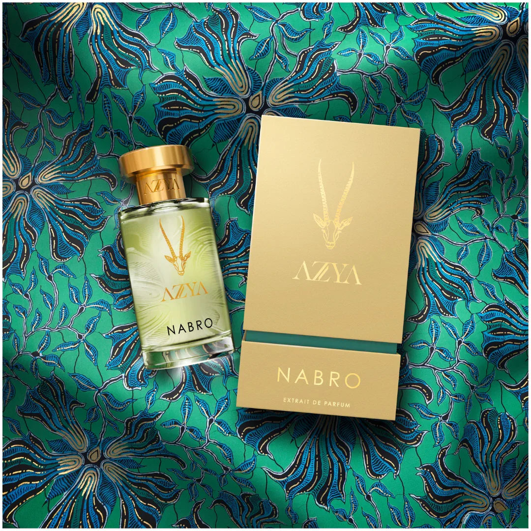 Parfümflasche und Verpackung mit der Aufschrift "Nabro" von "Azya". Beide sind goldfarben mit dekorativen grünen Details.