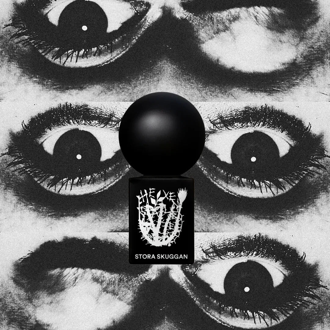 Parfümflasche mit schwarzer Kugelkappe und dem weißen Aufdruck "HEXENSALBE STORA SKUGGAN" vor einem surrealen Hintergrund.