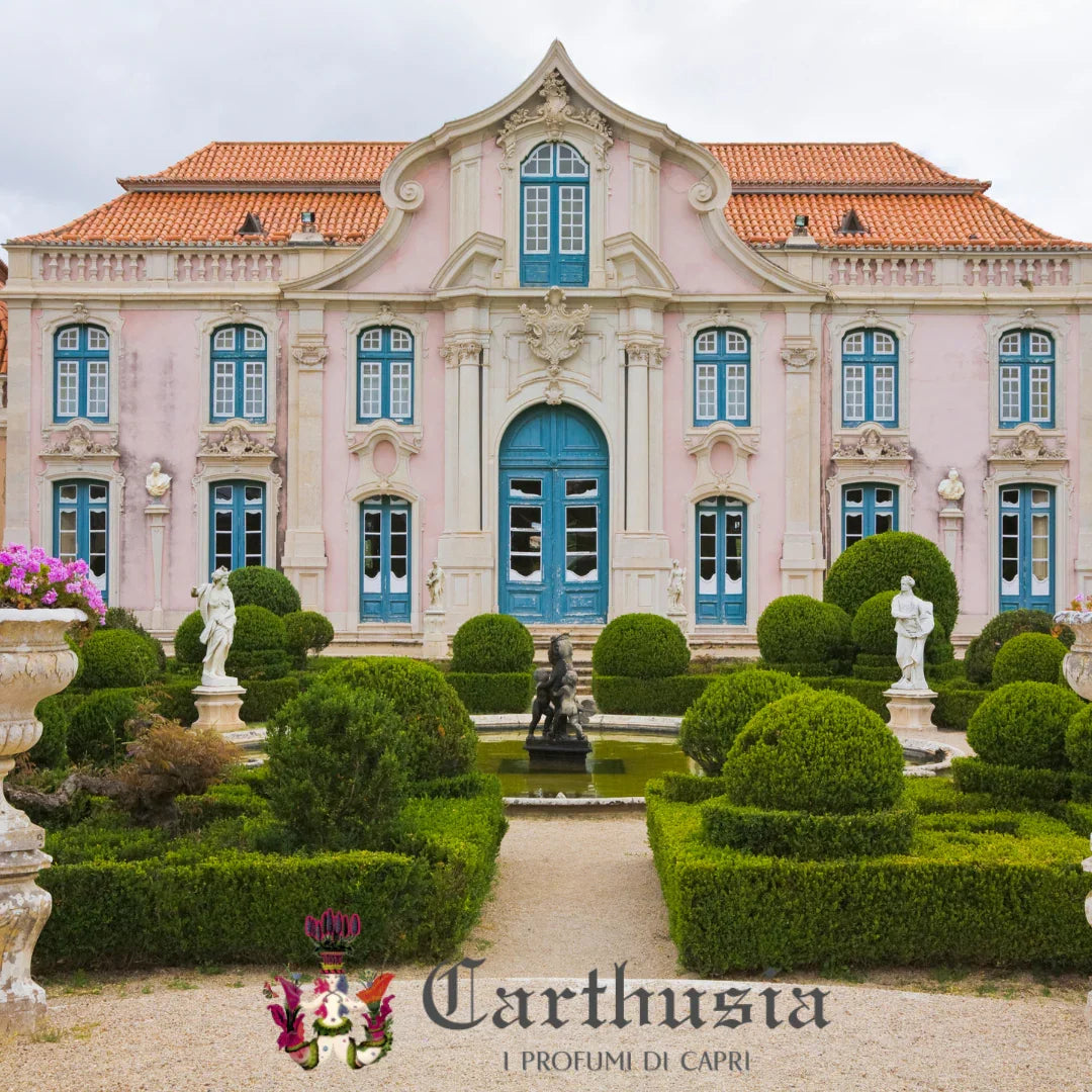 Elegantes Herrenhaus mit kunstvoll gestalteter Fassade, blauen Fensterläden und gepflegtem Garten. Carthusia - Frutto di Bacco Duftkerze.