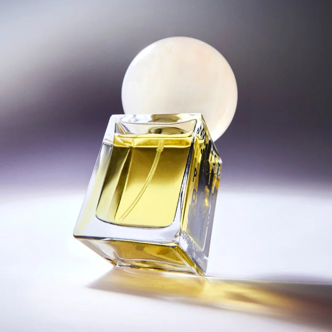 Parfümflasche "Mistpouffer" von Stora Skuggan, mit rundem, perlmuttfarbenem Verschluss und gelblichem Inhalt.