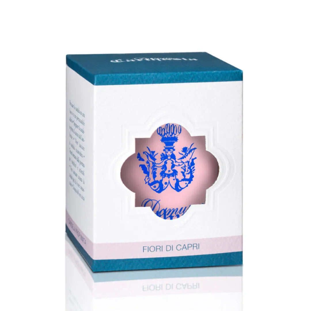 Weiße Duftkerzenverpackung mit blauem Logo und Sichtfenster. Titel: Fiori di Capri Duftkerze, Anbieter: Carthusia.