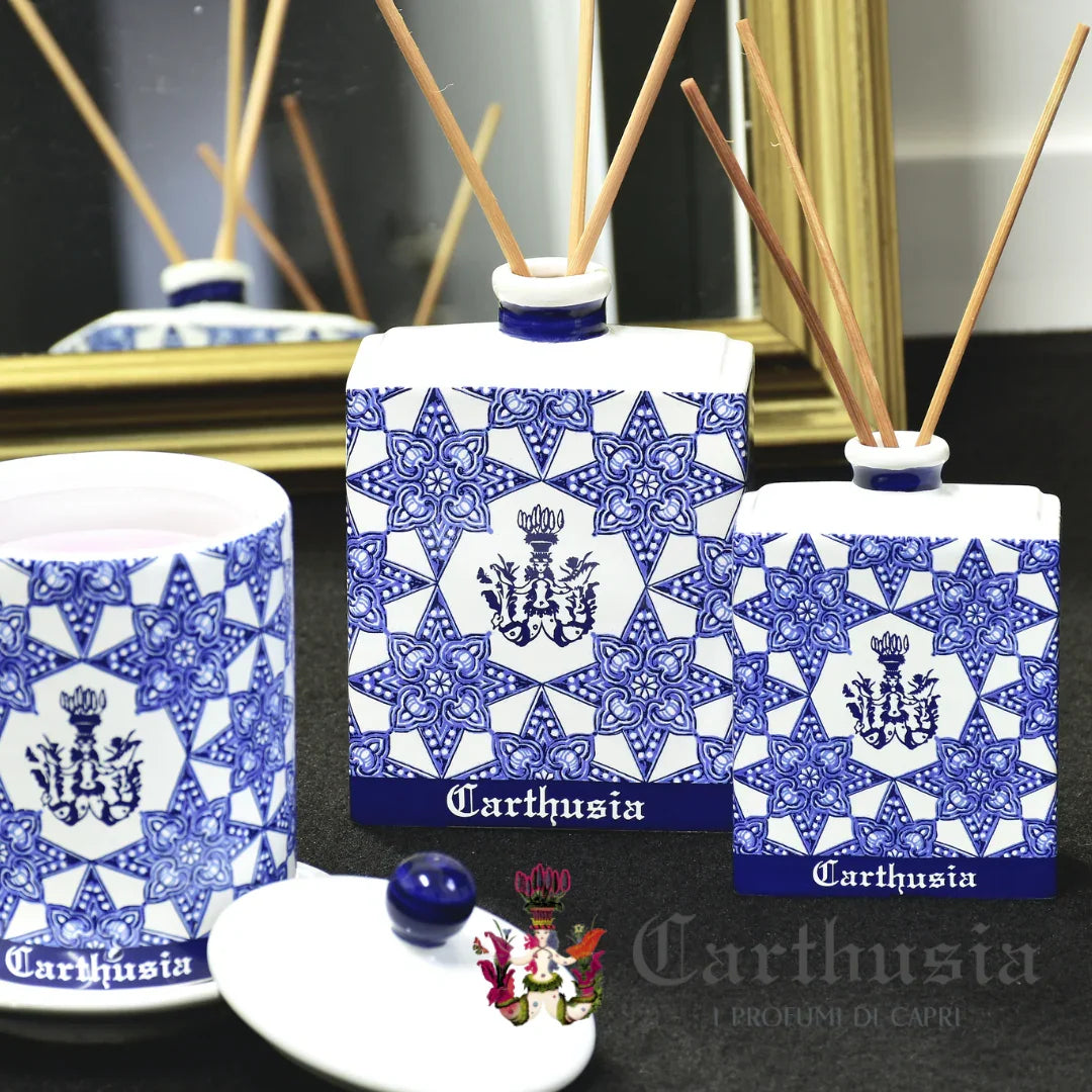 Carthusia Via Camerelle Diffuser mit weiß-blauer Flasche im geometrischen Design und Holzstäbchen, neben passendem Behälter.