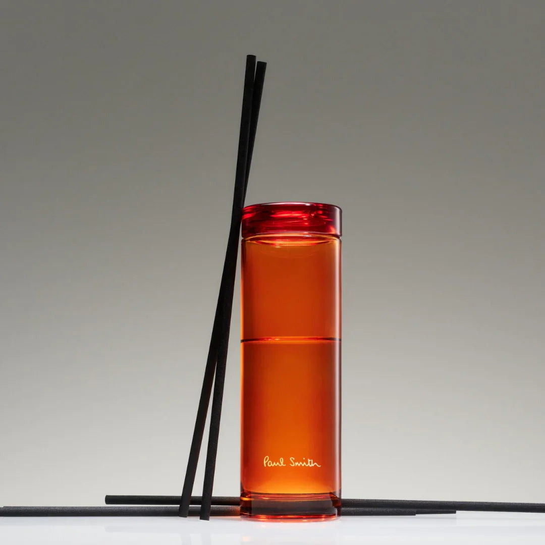 Roter Diffuser „Bookworm“ von Paul Smith mit schwarzem Deckel und mehreren schwarzen Stäbchen.