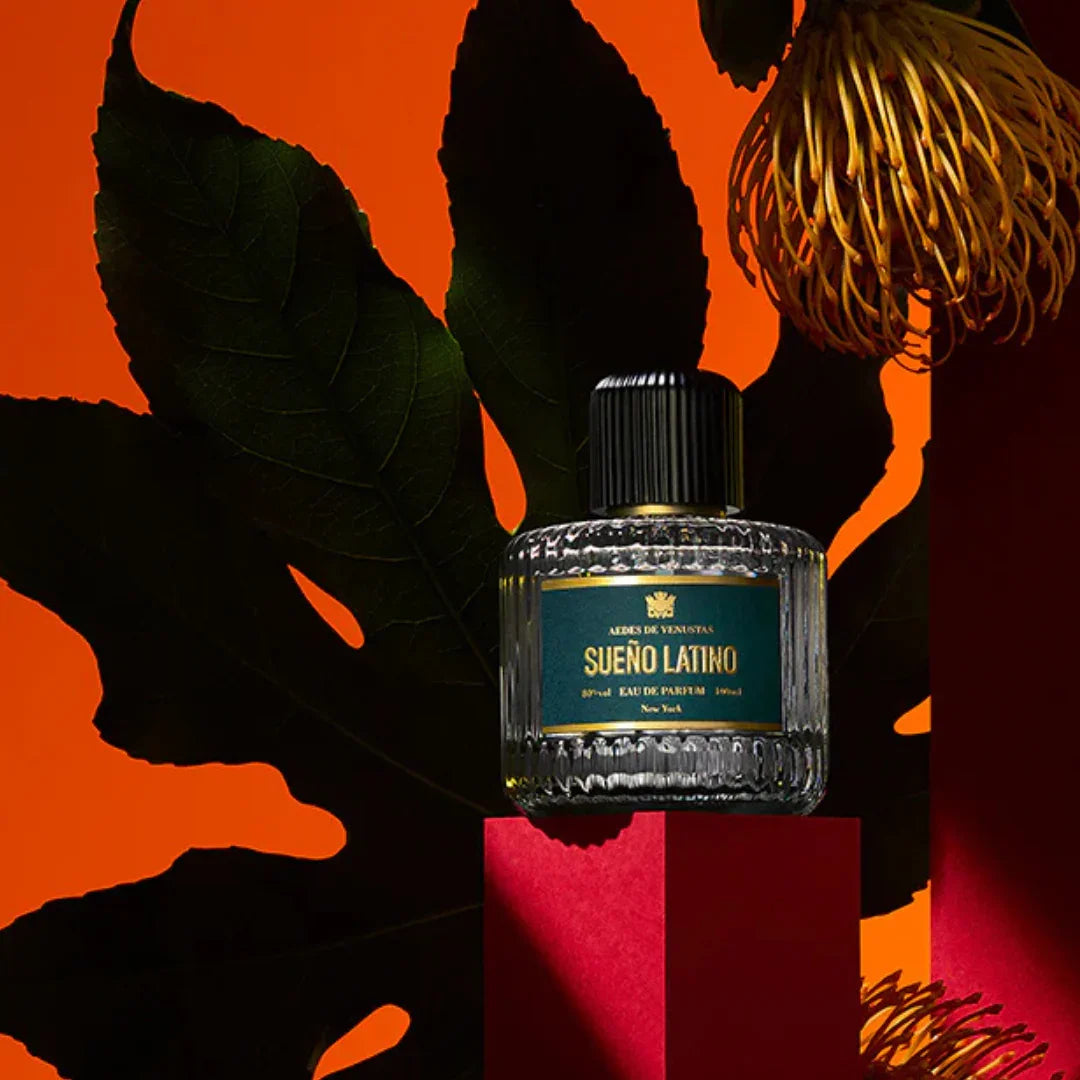 Aedes de Venustas Sueño Latino Eau de Parfum – der Flakon thront auf einem leuchtend roten Podest, kunstvoll inszeniert, ein Bild voller Leidenschaft und kreativer Eleganz – erlebe den Nischenduft bei scent amor