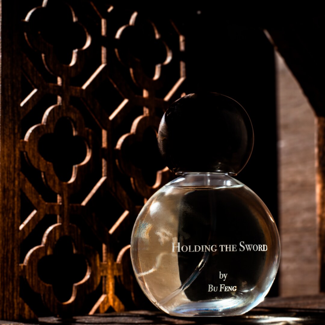 Bu Feng Eau de Parfum Holding the Sword Nischenduft Flakon vor Holzornament präsentierte bei scent amor Fachmann für feine Nischenparfums