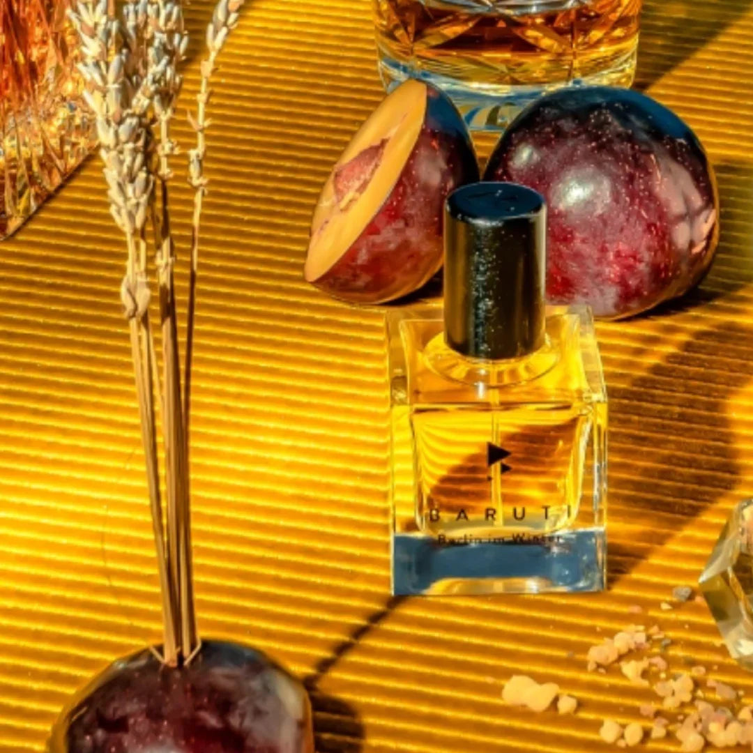 baruti berlin im winter exdp flakon auf gelbem untergrund vor einer geschnittenen pflaume