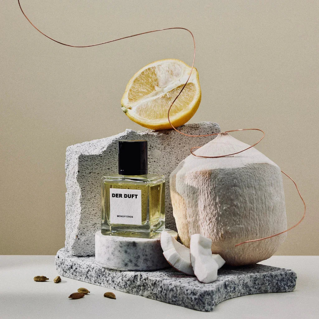 der duft monopteros flakon neben kokosnuss und zitrone