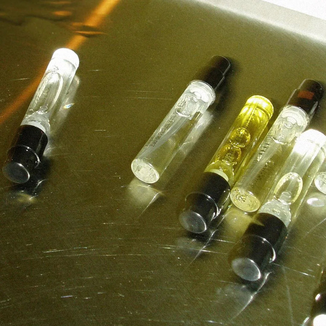 Mehrere kleine Duftproben mit schwarzen Verschlüssen, einige Fläschchen enthalten gelbe Flüssigkeit. Produkt: Discovery Set 8 * 2 ml. Anbieter: Kintsugi Perfumes. scent amor