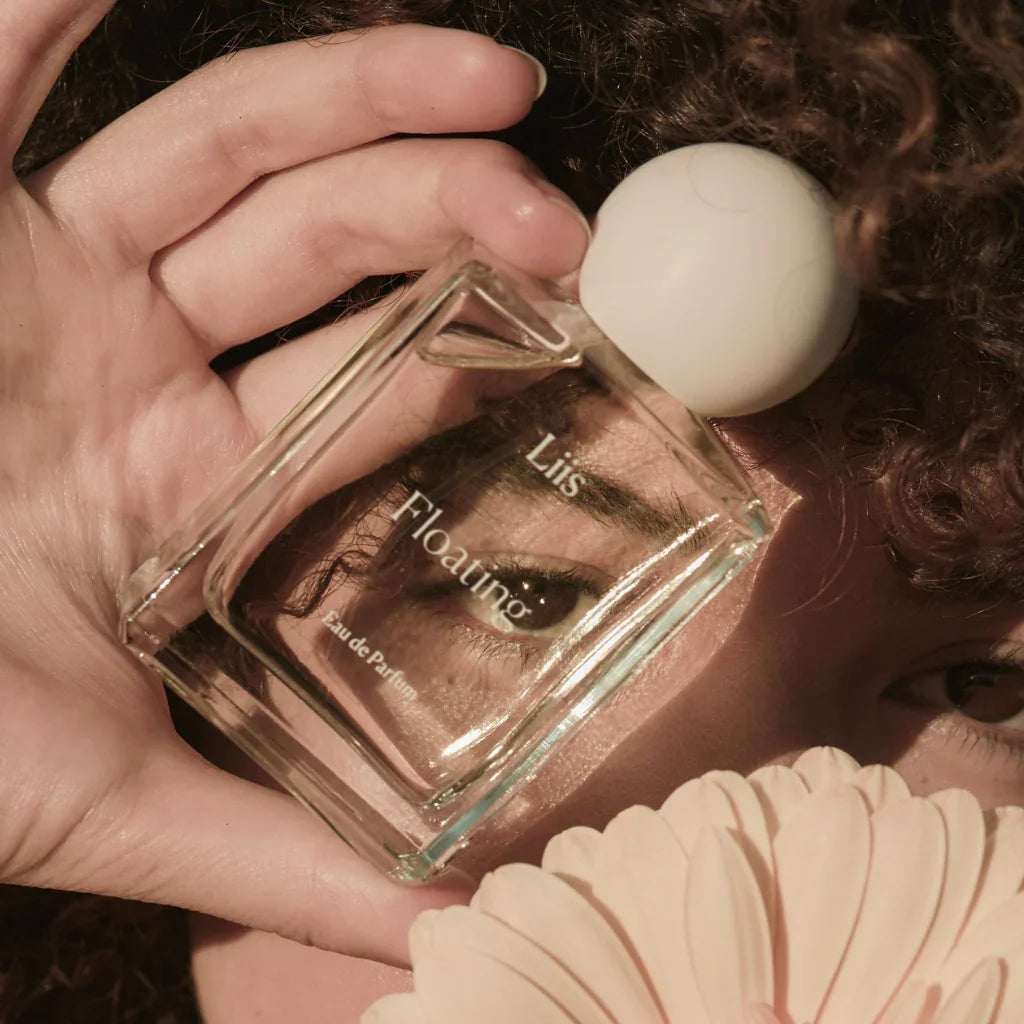 Liis Floating Eau de Parfum-Flakon, gehalten von einer Hand, mit transparentem Glas und kugelförmigem Verschluss.