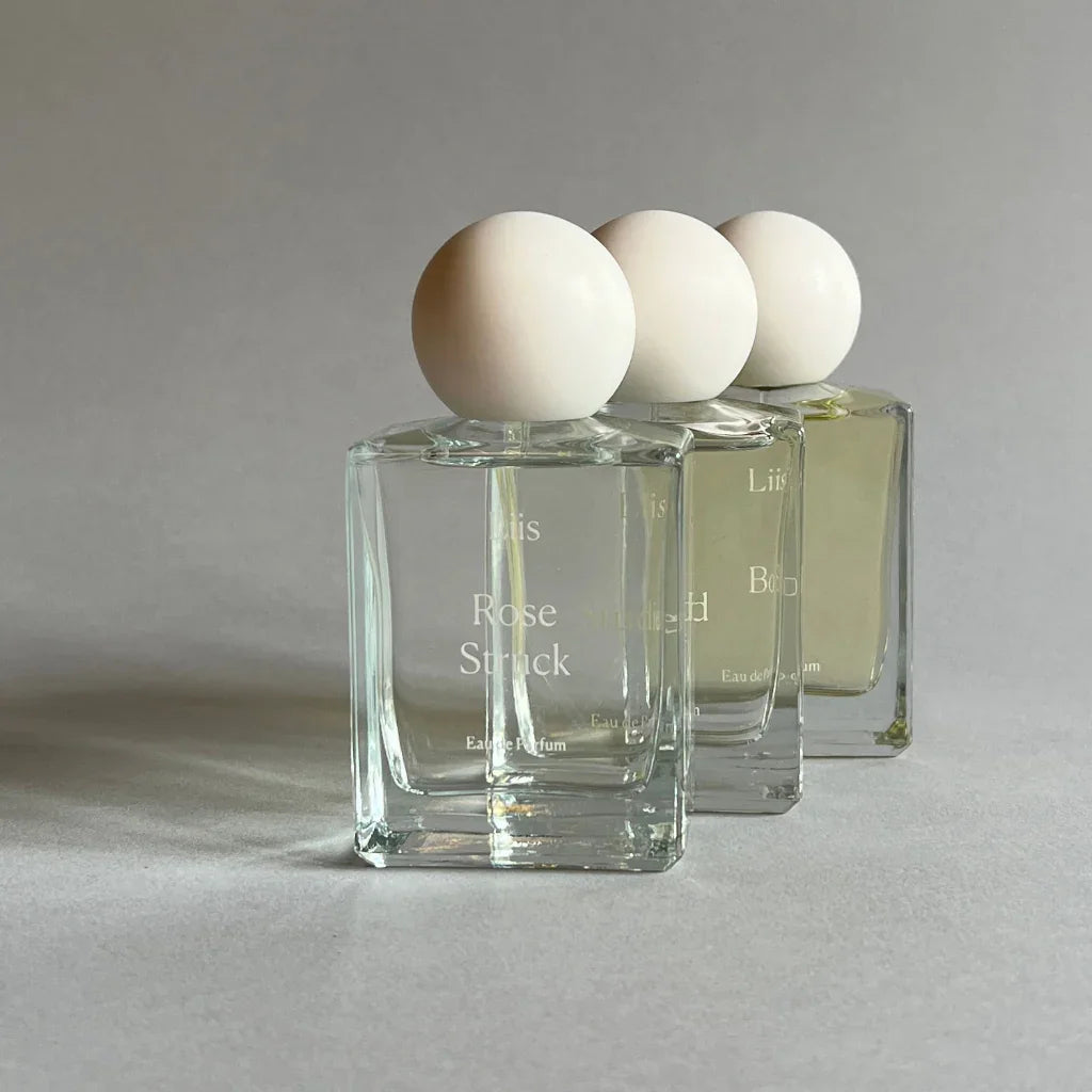 Parfümflakon "Rose Struck" von Liis. Drei klare Glasflakons mit weißem kugelförmigem Verschluss.
