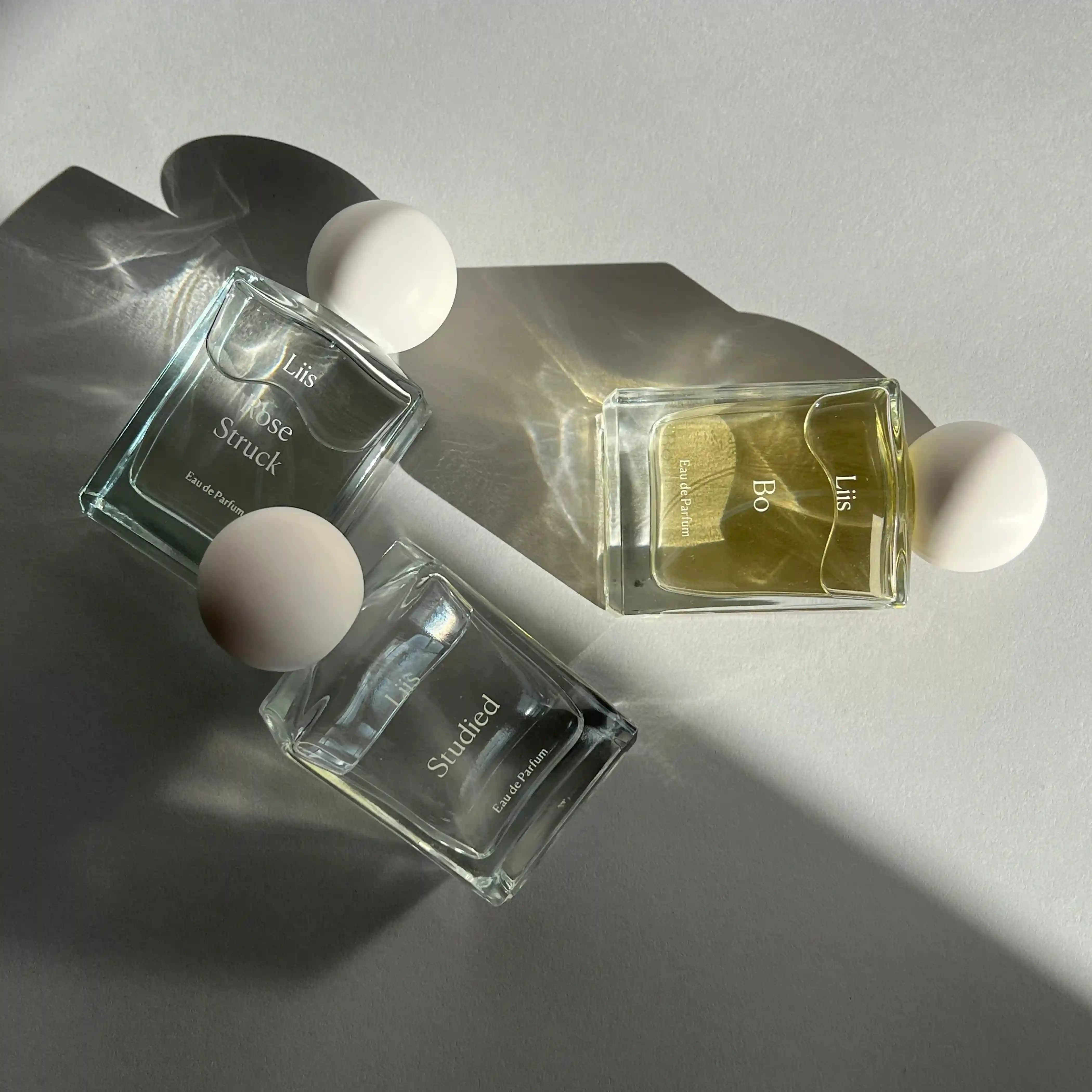 Drei Parfümflaschen mit weißen Kugelverschlüssen. Titel: "In this World", Hersteller: Liis.