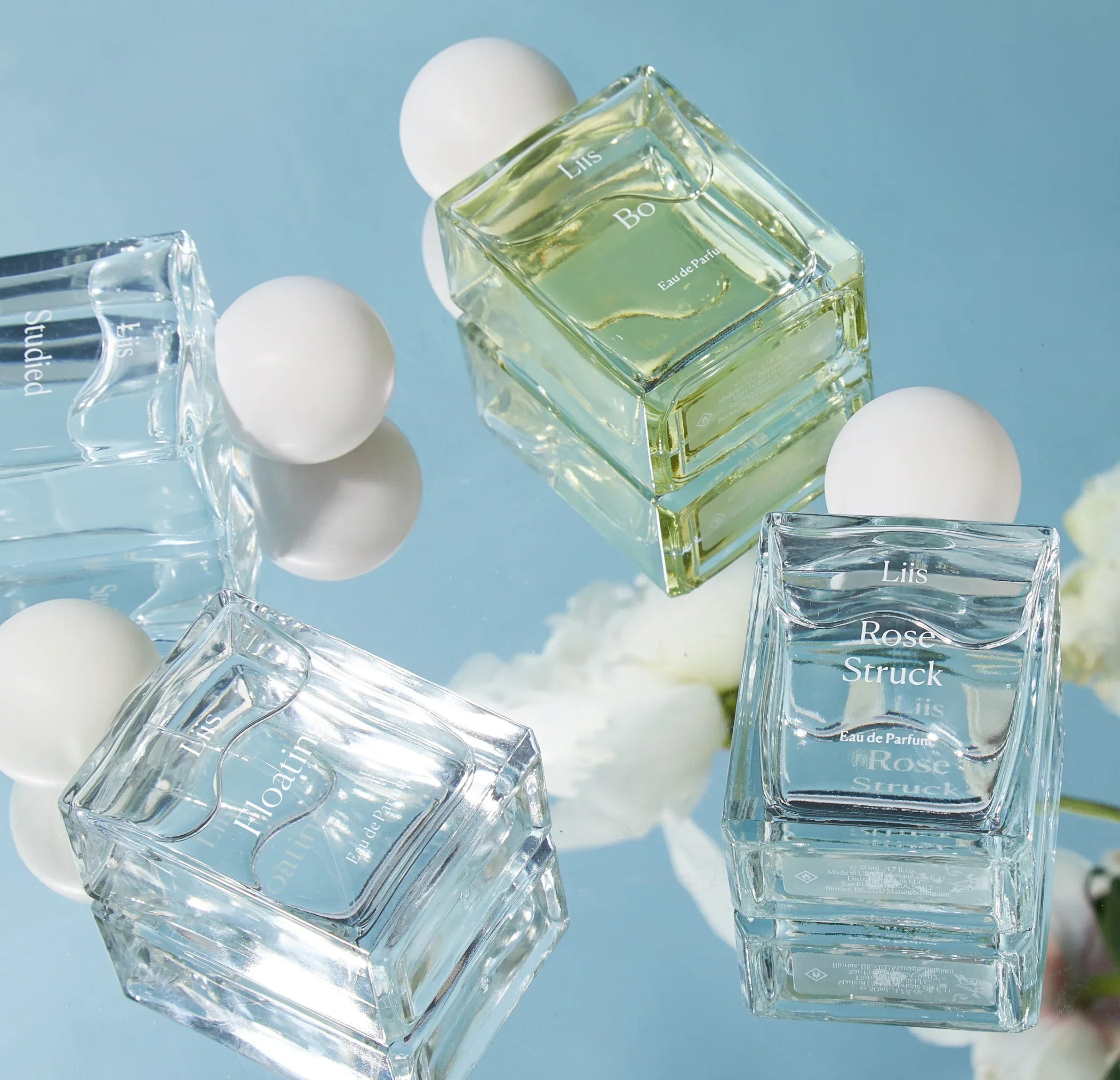 "In this World" Parfums von Liis, transparente und gelbliche Flaschen mit Kugelverschlüssen, auf spiegelnder Oberfläche.