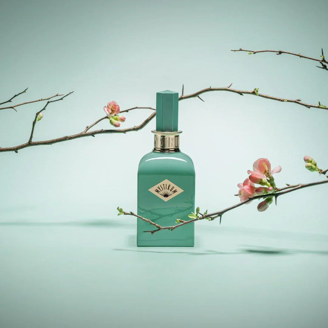 Mystikum The Geisha's Secret Garden Eau de Parfum – vor mintfarbenem Hintergrund mit Kirschblüten inszeniert, zart und geheimnisvoll wie die Fantasy Collection selbst – entdecke ihn bei scent amor