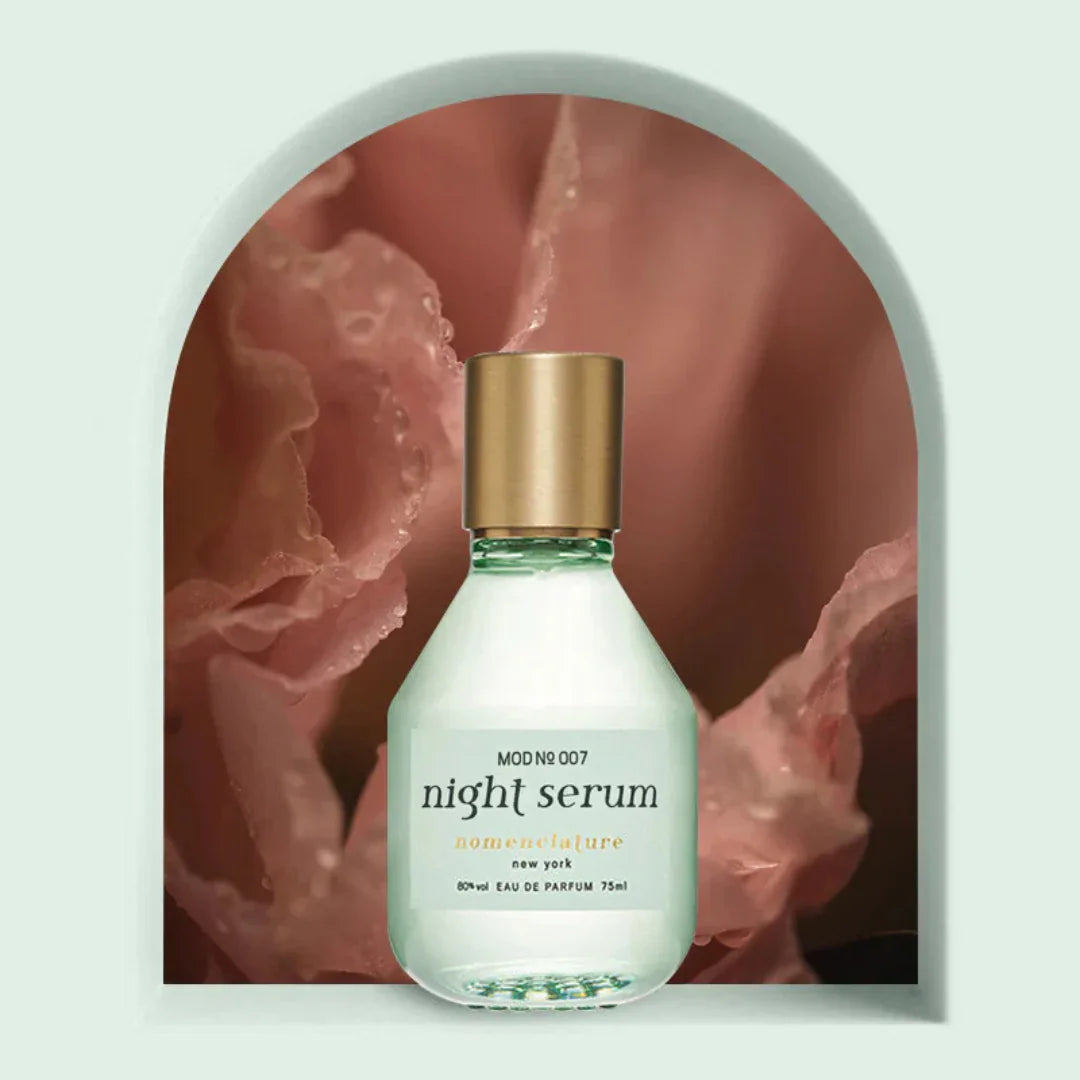 nomenclature Night Serum Eau de Parfum – der Flakon steht vor zarten rosanen Blüten, ein Bild voller floraler Eleganz und subtiler Leichtigkeit