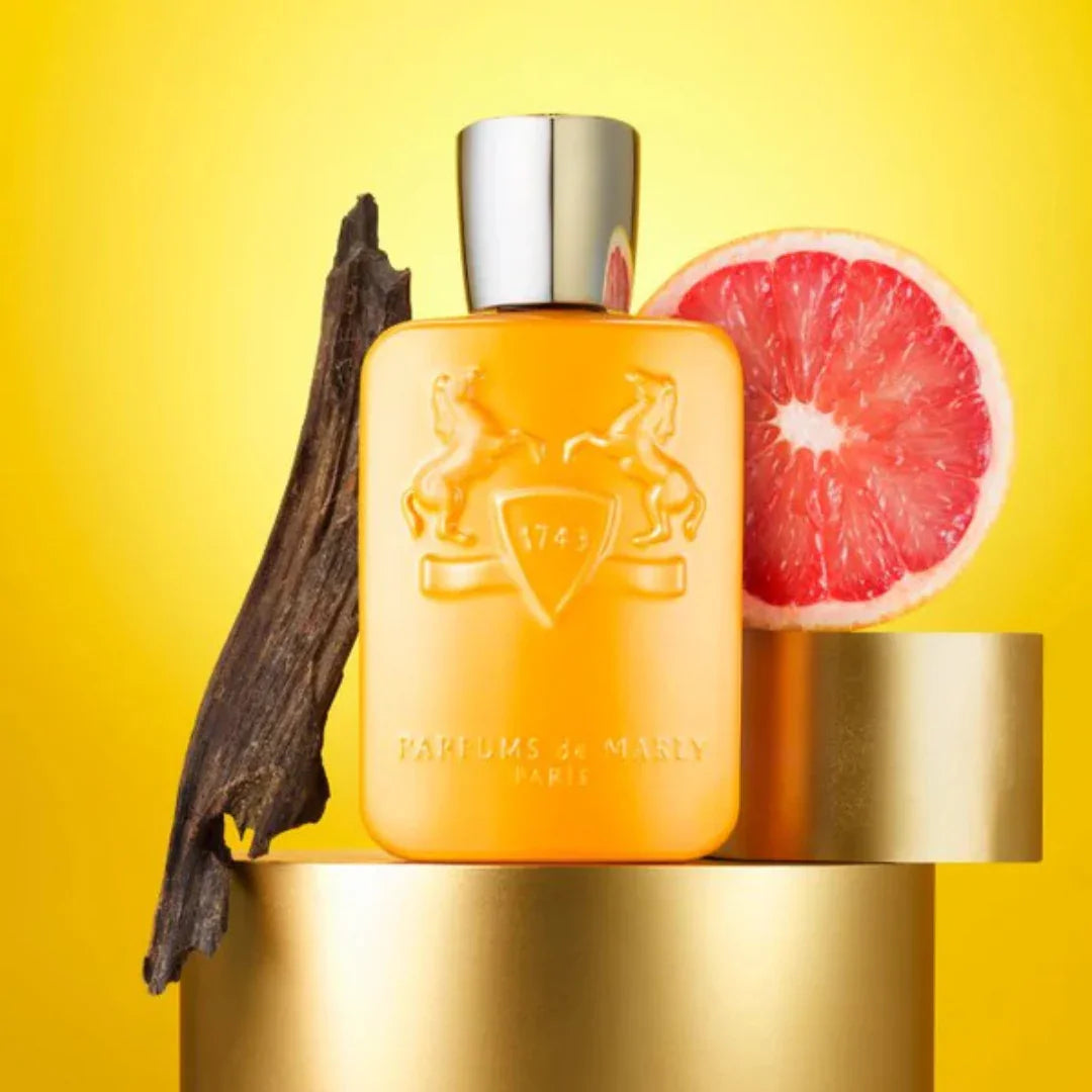 Parfums de Marly Perseus Eau de Parfum – der Flakon steht neben edlem Holz und einer rosa Grapefruit, ein Bild, das die frische, holzige und zitrische Duftkomposition kunstvoll inszeniert – erlebe es bei scent amor