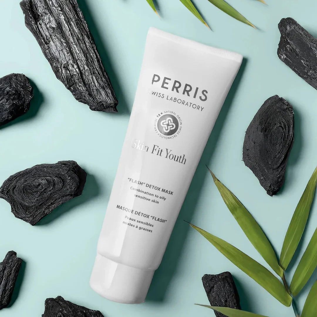 Perris Swiss Laboratory Skin Fit Youth Flash Detox Mask – die Tube, umgeben von Kohlesteinen und Blättern, als Symbol für die reinigende Kraft der Natur – erlebe die Gesichtsmaske bei scent amor