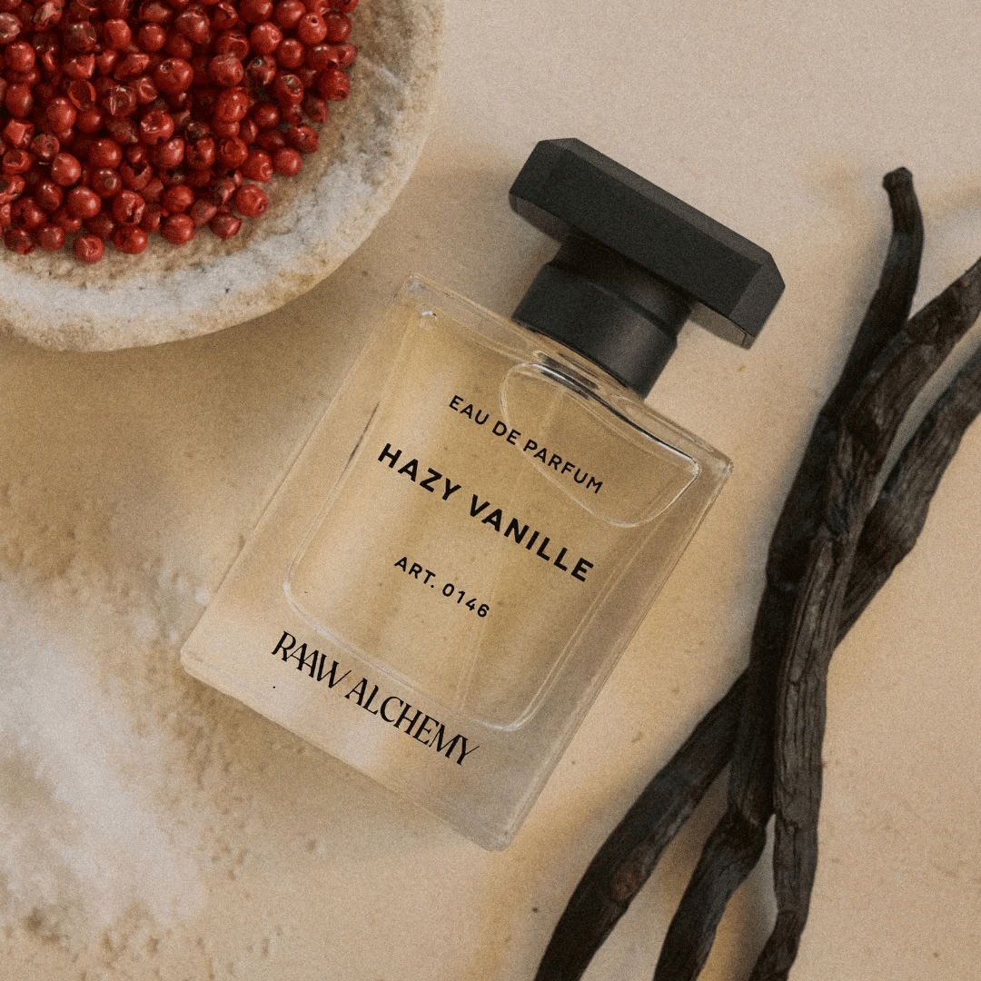 RAAW ALCHEMY Hazy Vanille Eau de Parfum Nischenduft Flakon vor rosa Pfefferkörnern und Vanille Schote präsentiert bei scent amor