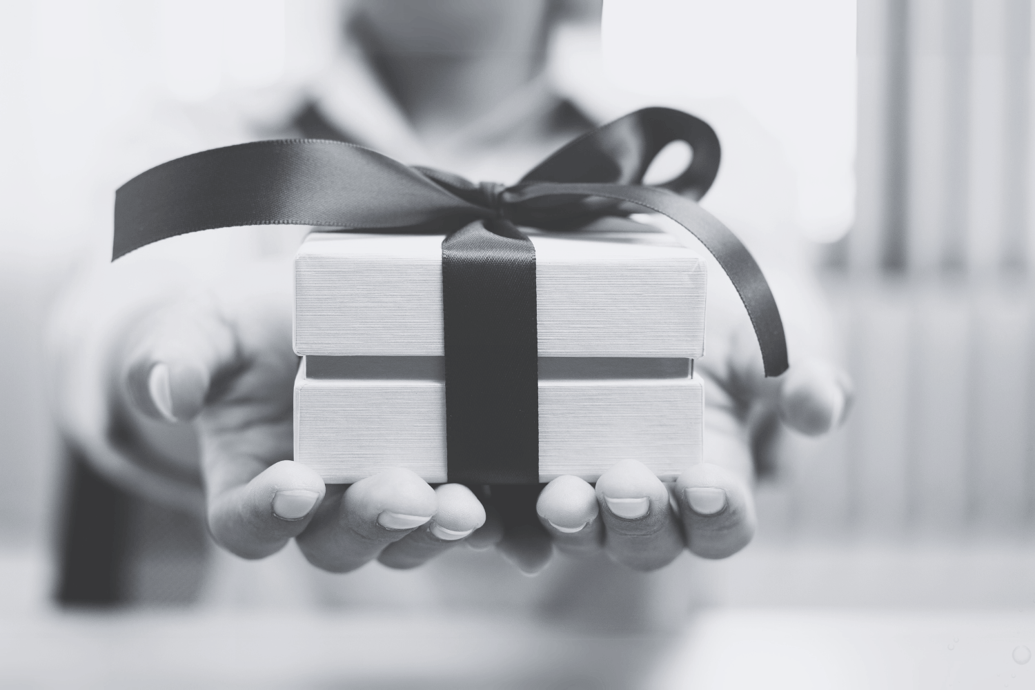 zwei Hände übergeben ein Geschenk in schwarz-weiß