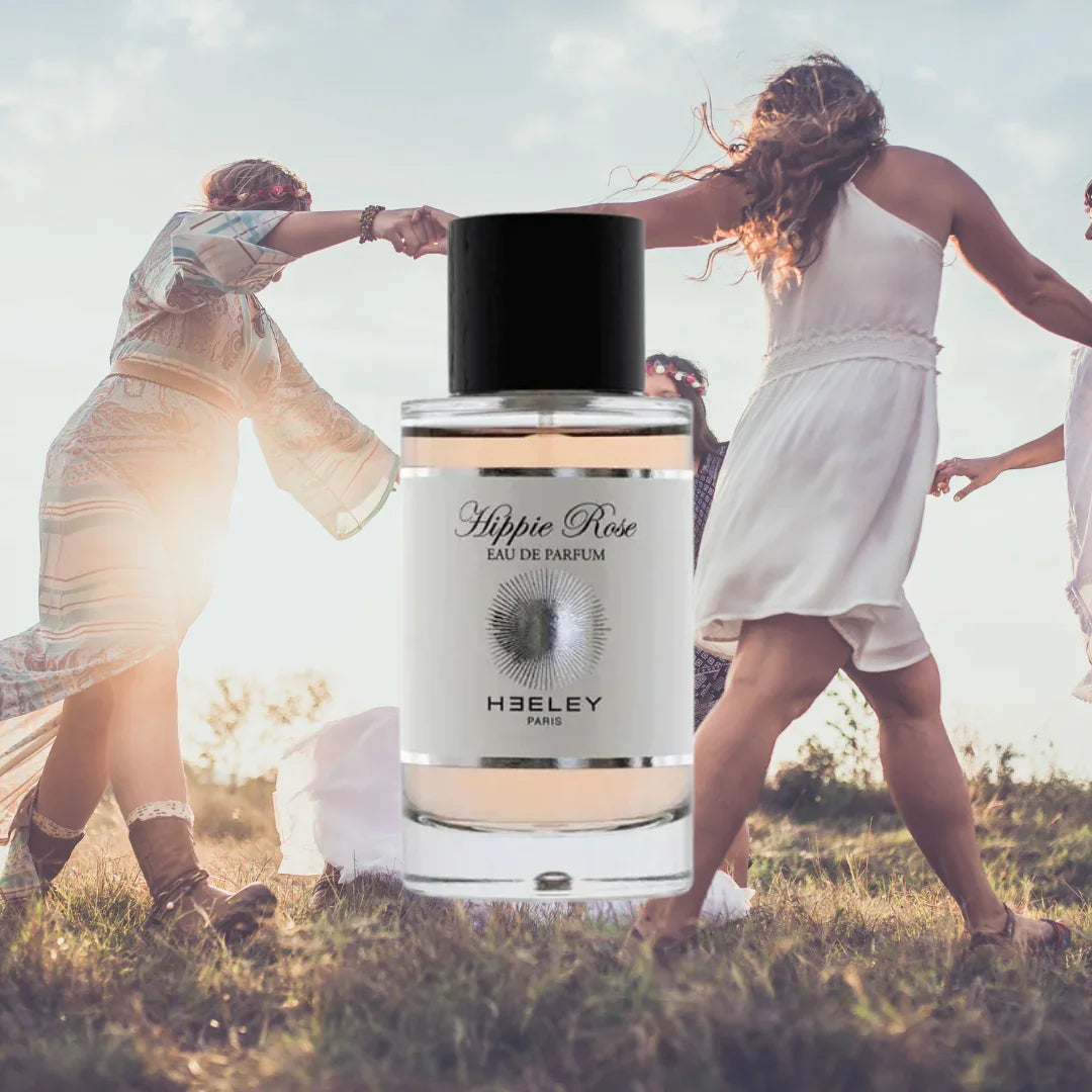 Parfümflasche mit Aufschrift "Hippie Rose Eau de Parfum" und "Heeley Paris". Im Hintergrund tanzen mehrere Personen im Freien.
