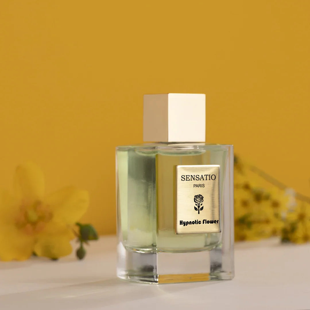 Eleganter Flakon von Sensatio Paris mit hypnotisch-blumigem Charakter -Hypnotic Flower als Eau de Parfum, vor gelbem Hintergrund und gelben Blumen, bei scent amor