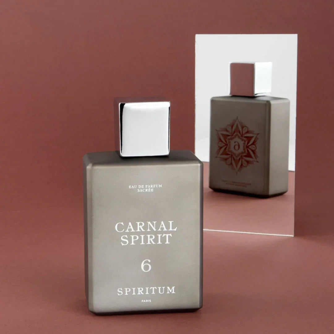 Spiritum Paris CARNAL SPIRIT Eau de Parfum – der Flakon steht auf einem zarten rosanen Hintergrund vor einem Spiegel, der seine elegante Vorder- und Rückseite reflektiert – ein visuelles Spiel von Transparenz und Tiefe, das die Dualität des Dufts enthüllt – erlebe es bei scent amor