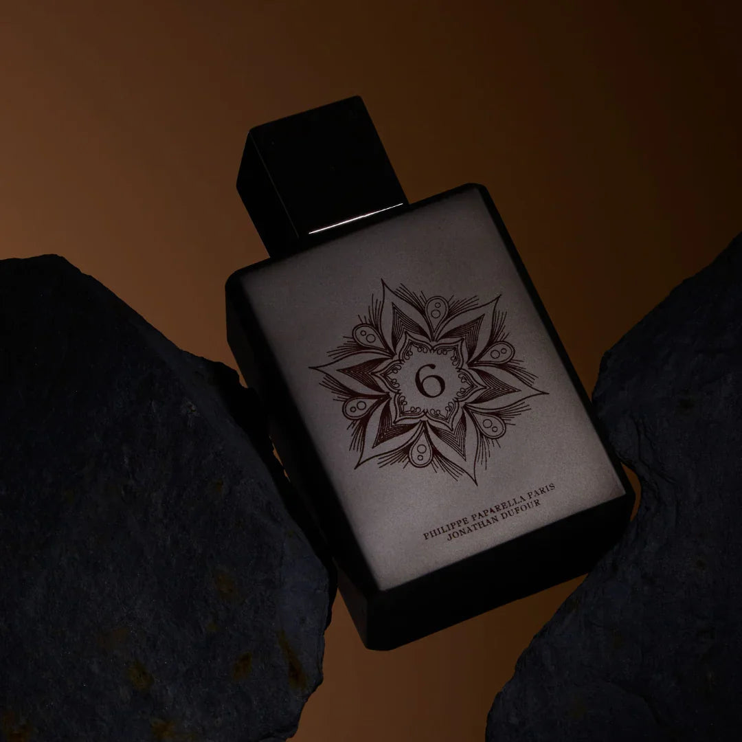 Spiritum Paris CARNAL SPIRIT Eau de Parfum – der Flakon ruht schräg zwischen zwei Steinen, als wäre er in einer Felsenkluft gefangen – eine Szene voller Spannung und Sinnlichkeit, die den Duftcharakter lebendig werden lässt – entdecke es bei scent amor