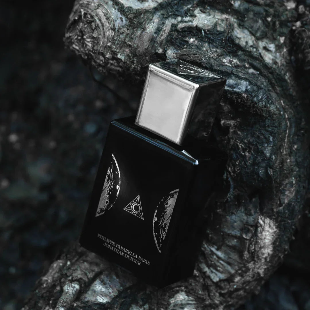 Spiritum Paris JACOB Eau de Parfum – der Flakon ruht schräg auf einem gebogenen Holzstamm, als würde er sich der Natur anpassen – eine Szene voller Balance und Poesie, die die Tiefe des Dufts spiegelt – entdecke es bei scent amor