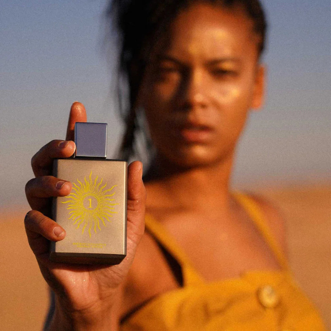 Eine Frau hält den Flakon von Spiritum Paris SOLAR SOUL Eau de Parfum in der Hand, das Sonnenlicht tanzt auf der Glasoberfläche, erlebe den Moment bei scent amor