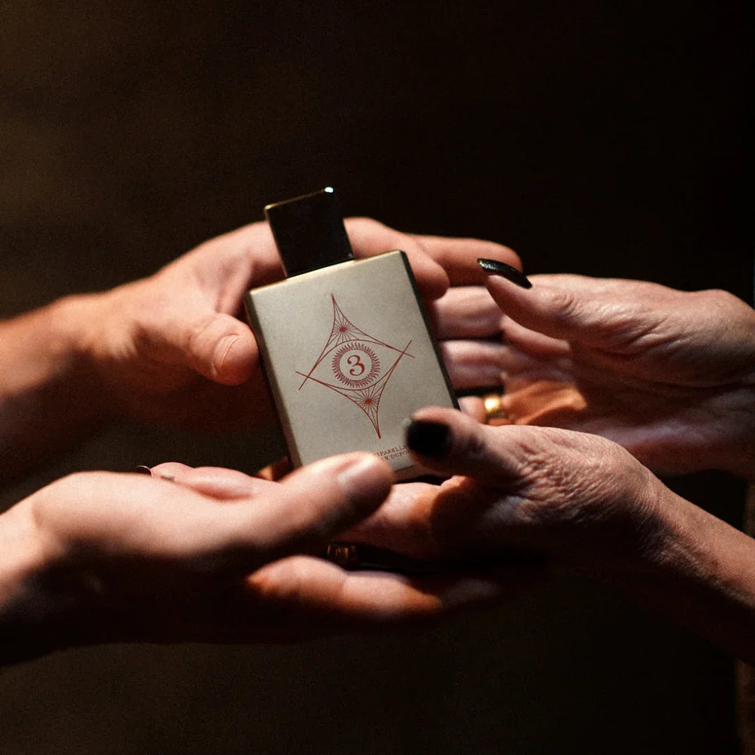 Spiritum Paris WISDOM UNIVERSE Eau de Parfum – junge und alte Hände mit schwarzem Nagellack umschließen den Flakon, eine sinnbildliche Verbindung von Generationen und Duft – lass Dich inspirieren bei scent amor