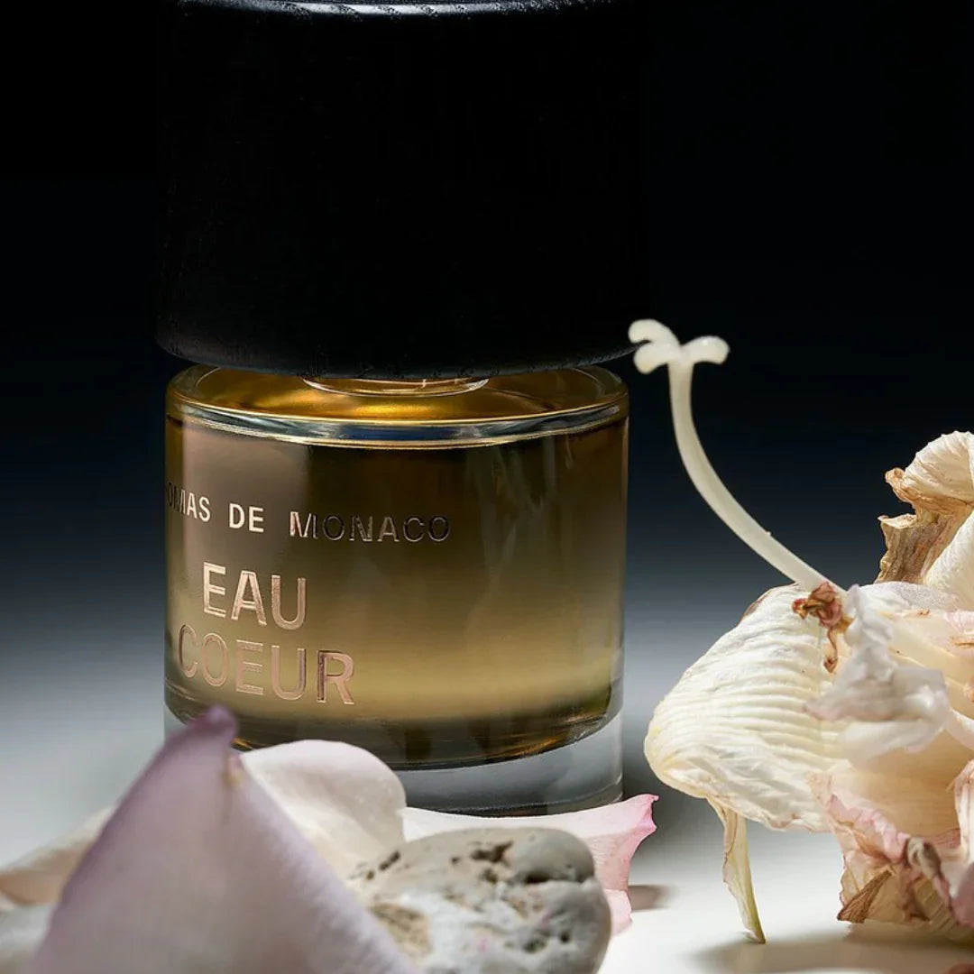 Thomas De Monaco Eau Coeur Flakon zwischen Blumen mit dunklem Hintergrund- luxuriöses Eau de Parfum erhältlich bei scent amor