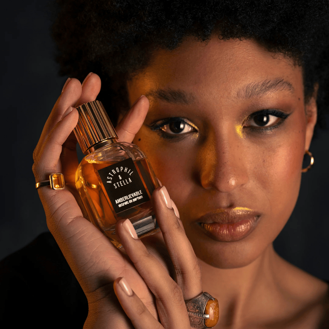 Astrophil & Stella AMBERLIEVABLE Eau de Parfum, sinnliche Duftpräsentation mit Model, goldschimmernder Amberduft in eleganter Handhaltung, künstlerisch und intim inszeniert, erhältlich bei scent amor.