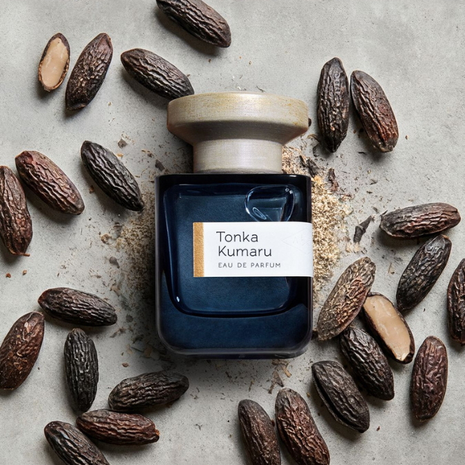 Atelier Materi Tonka Kumaru Eau de Parfum, Duftflakon umgeben von Tonkabohnen, natürliche und warme Duftkomposition, erhältlich bei scent amor.