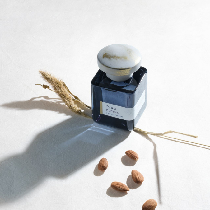 Atelier Materi Tonka Kumaru Eau de Parfum, stilvoll inszenierter Duftflakon mit natürlichen Elementen und weichem Licht, elegant und ruhig, erhältlich bei scent amor.
