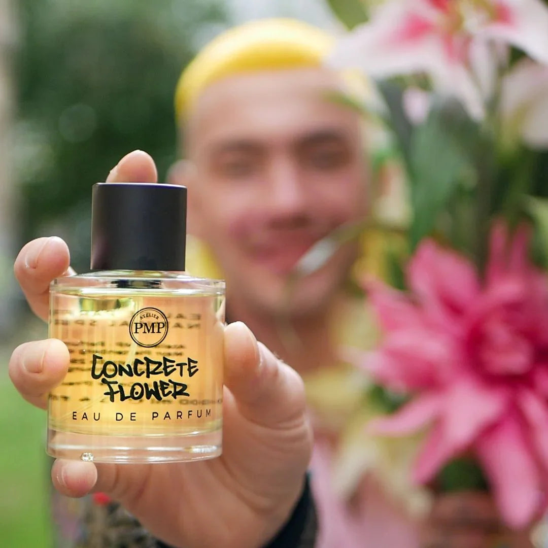 atelier pmp flakon von dem eau de parfum concrete flower gehalten von einer personen neben blumen
