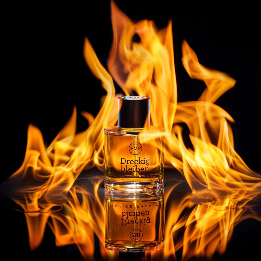 flakon von dem eau de parfum dreckig bleiben von atelier pmp vor brennendem hintergrund