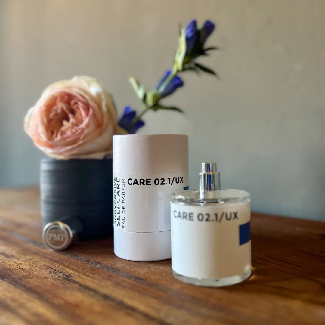 flakon von dem eau de parfum care 02.1/ux von atelier pmp neben der box und vor einer blume