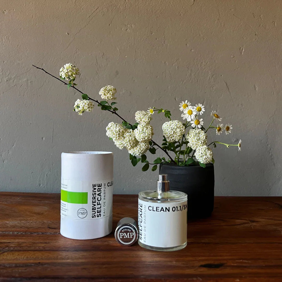 geöffneter flakon und die box von dem eau de parfum clean 01.1/sn von atelier pmp vor weissen Blumen