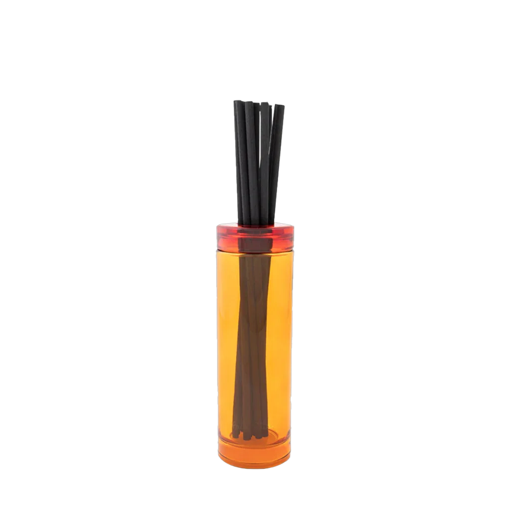 Ein transparenter Duftstäbchen-Diffuser mit orangefarbenem Behälter, gefüllt mit schwarzen Stäbchen. Produkt: Bookworm Diffuser von Paul Smith.