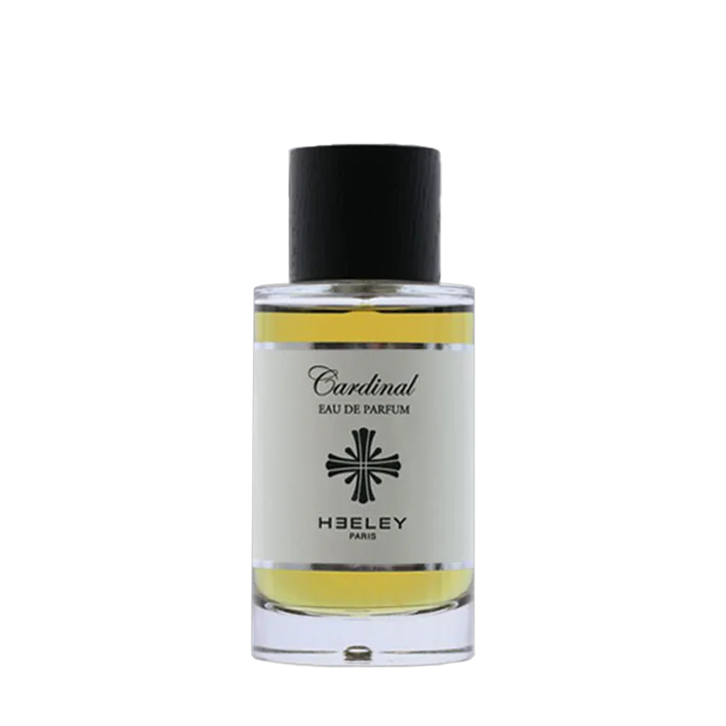 Das Bild zeigt ein Parfümfläschchen mit der Aufschrift "Cardinal Eau de Parfum" von der Marke "Heeley". Der Glasflakon hat eine schwarze Kappe und das Parfüm ist gelblich gefärbt.