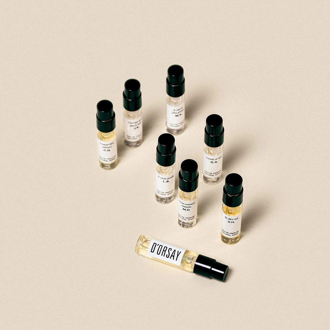 D’Orsay Les Découvertes Olfactives Discovery Set, einzelne Duftproben locker auf hellem Untergrund verteilt mit Fokus auf einer liegenden Probe, erhältlich bei scent amor.