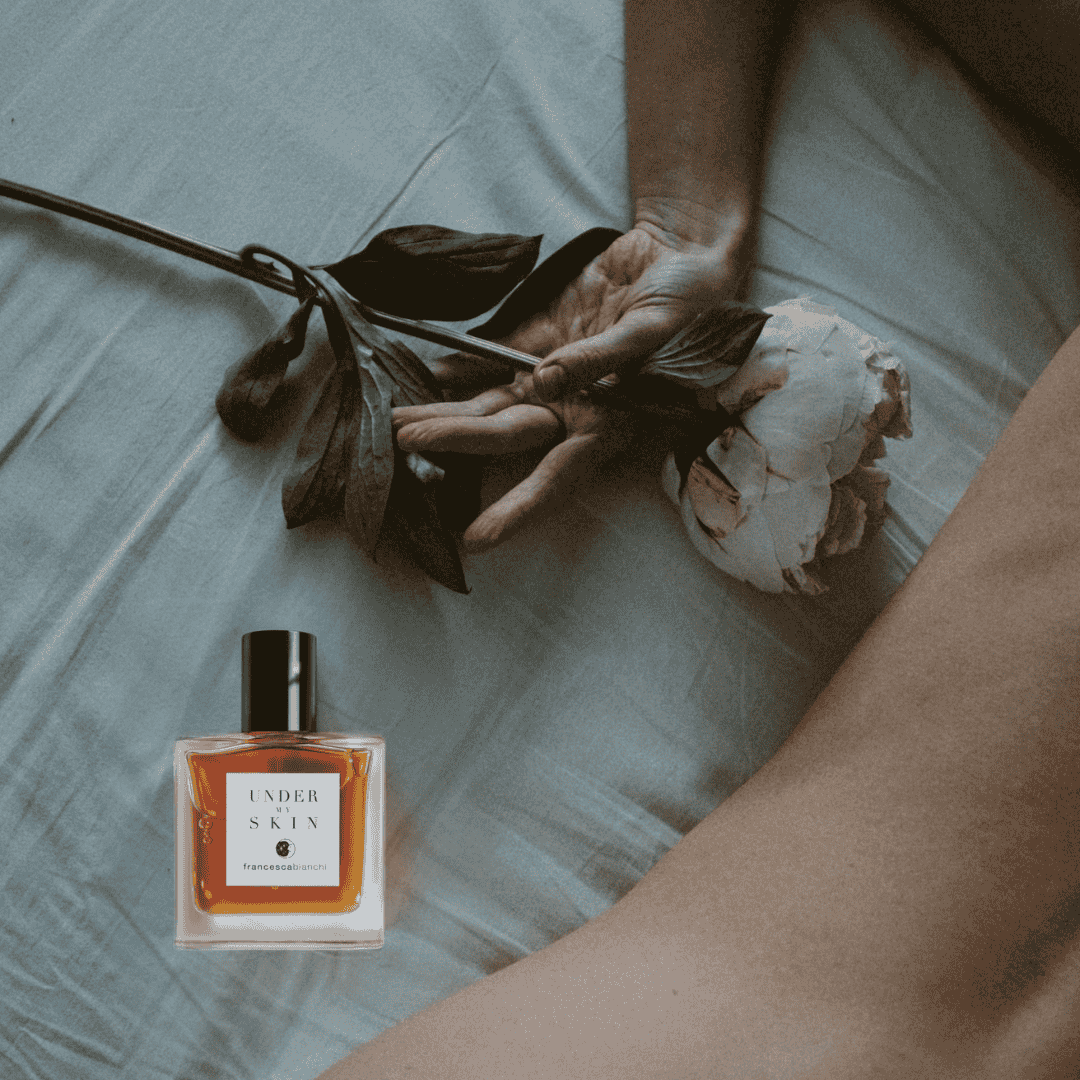 Flakon von Francesca Bianchi Under My Skin Extrait de Parfum auf Matratze neben Rose und nacktem Körper, erlebe ihn bei scent amor