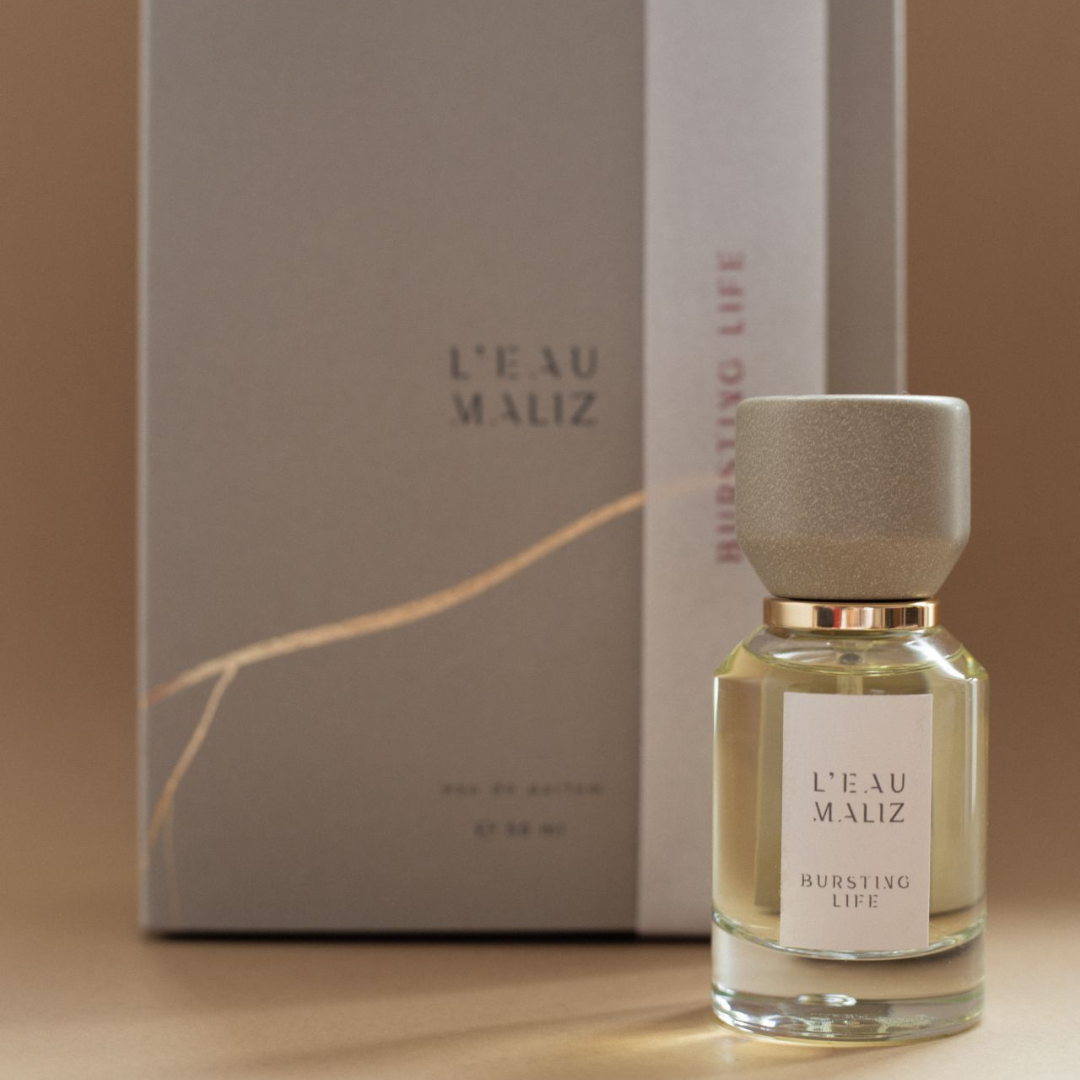 L’Eau Maliz Bursting Life Eau de Parfum, Flakon vor der Originalverpackung inszeniert, stilvoll und hochwertig, erhältlich bei scent amor.