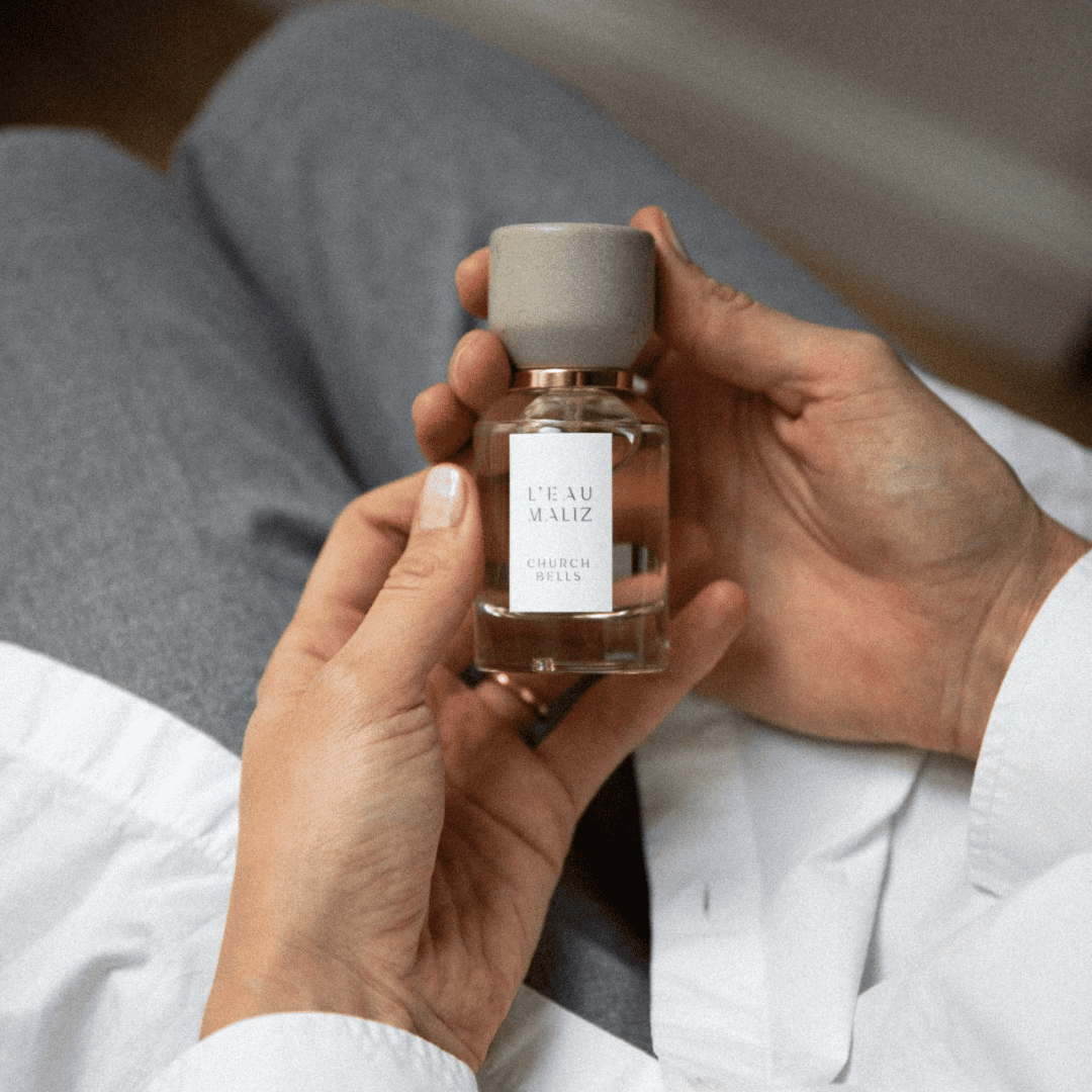 L’Eau Maliz Church Bells Eau de Parfum, Flakon in der Hand gehalten, warmes Lifestyle-Motiv mit persönlicher Note, erhältlich bei scent amor.
