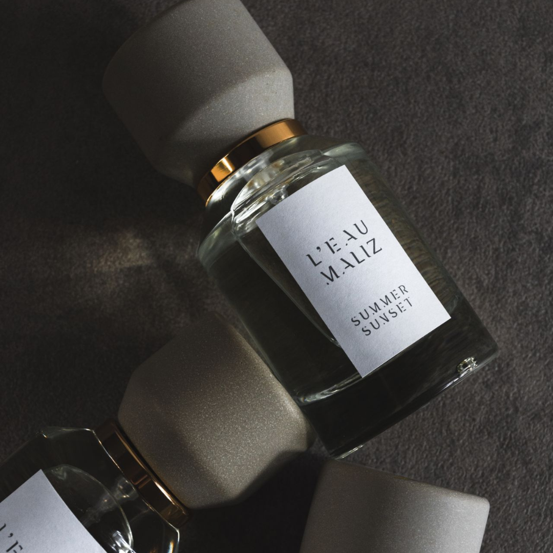 L’Eau Maliz Summer Sunset Eau de Parfum, Detailaufnahme des Flakons mit sanftem Lichtspiel, modern und ruhig inszeniert, erhältlich bei scent amor.