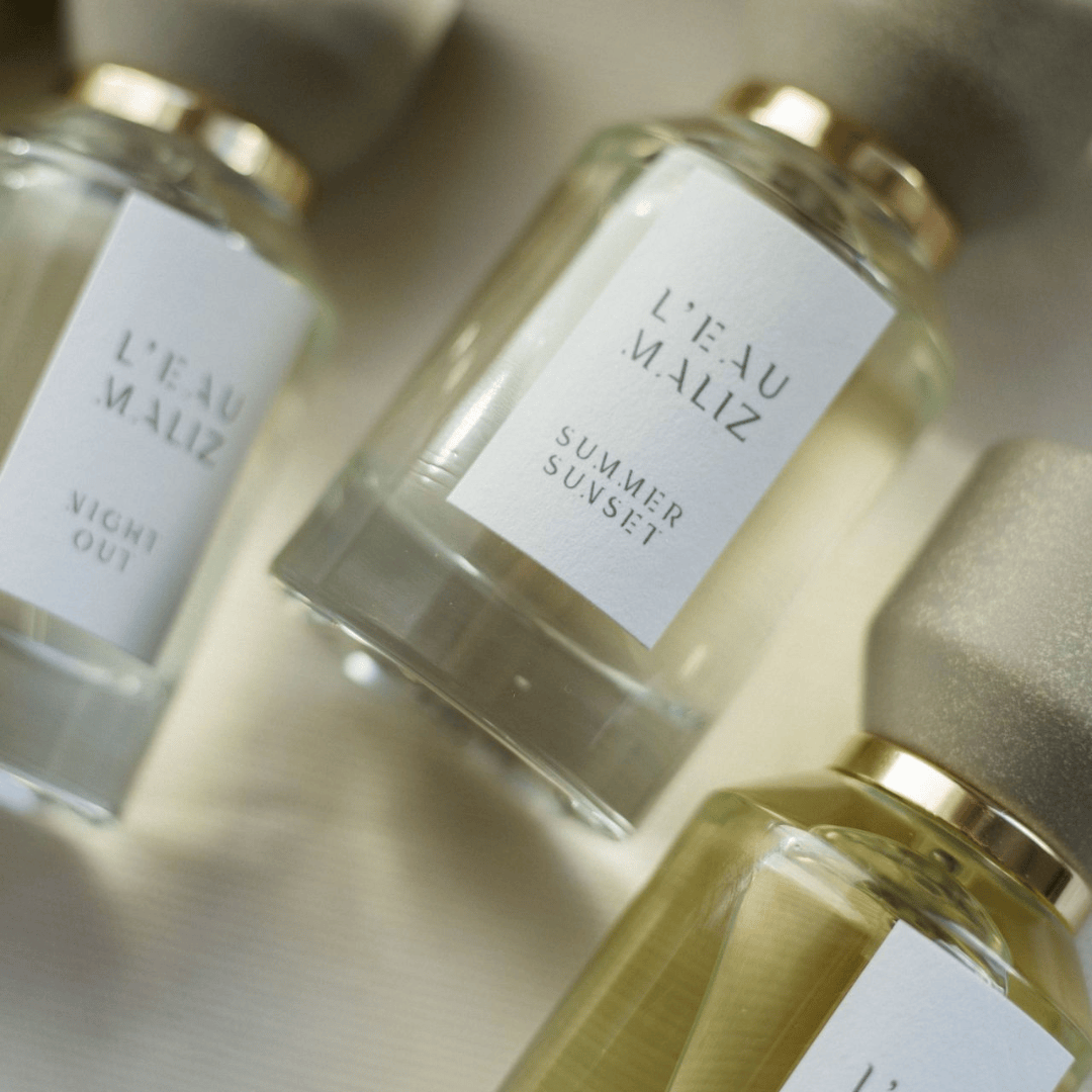 L’Eau Maliz Summer Sunset Eau de Parfum, mehrere Flakons in harmonischer Duftkomposition arrangiert, elegant und modern, erhältlich bei scent amor.