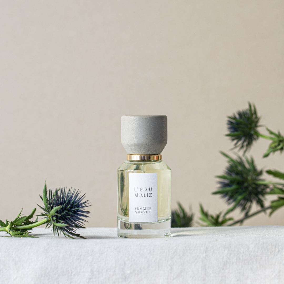 L’Eau Maliz Summer Sunset Eau de Parfum, Duftflakon in natürlicher Mood-Szene mit floralen Akzenten, leicht und sommerlich, erhältlich bei scent amor.