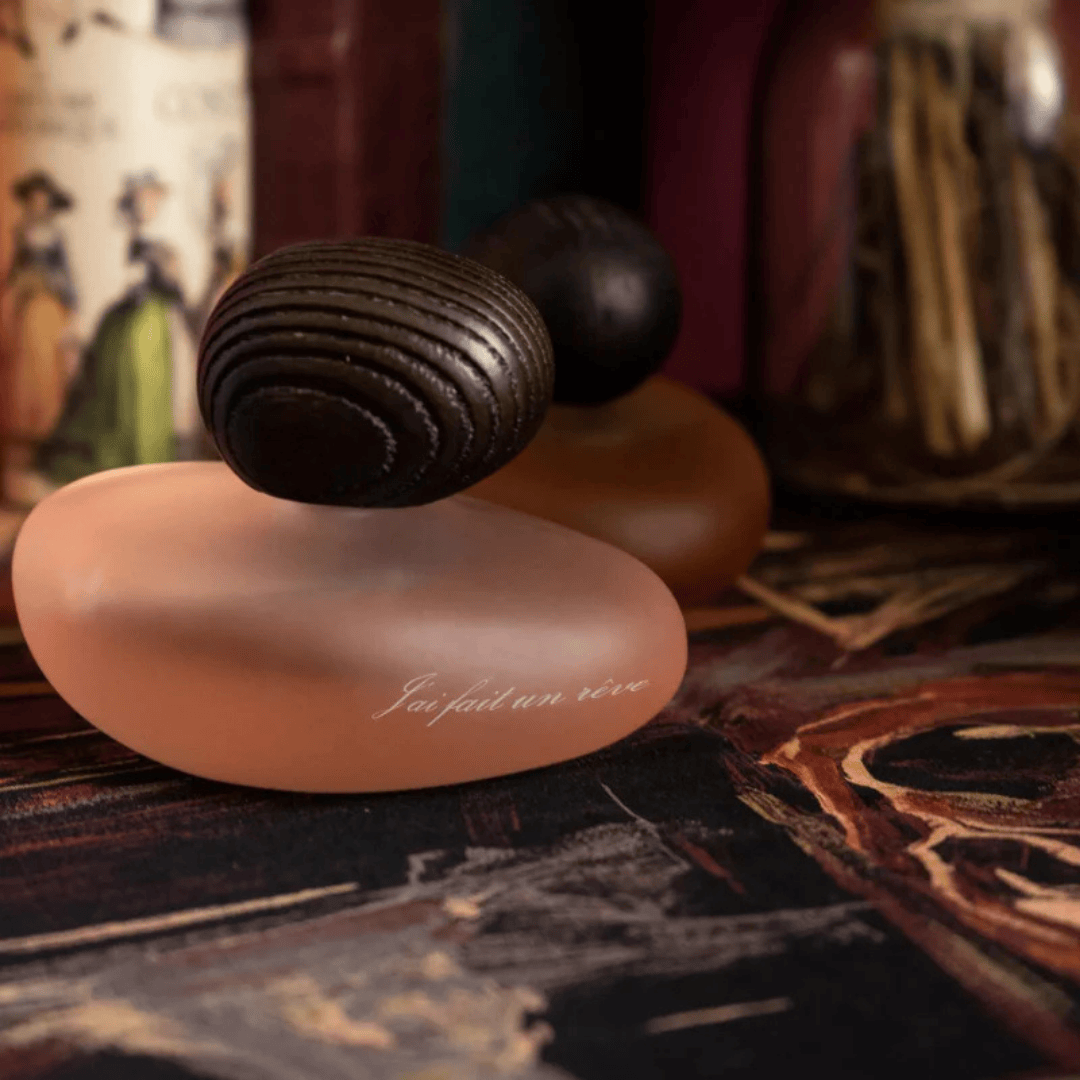 Majda Bekkali J’ai fait un rêve Clair Extrait de Parfum, roséfarbener Flakon auf dunkler Holzoberfläche inszeniert, warm und künstlerisch, erhältlich bei scent amor.