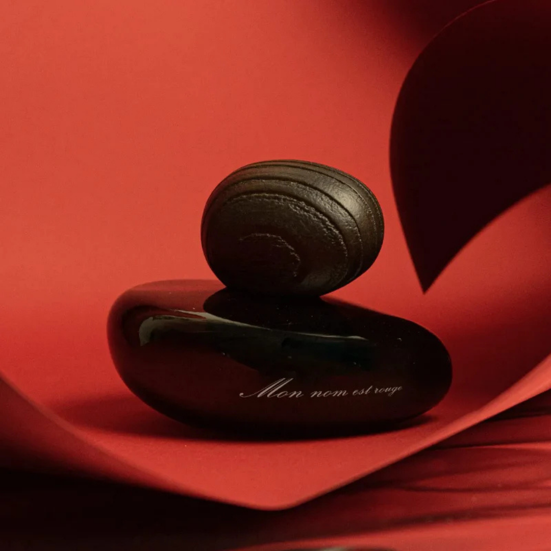 Majda Bekkali Mon Nom est Rouge Extrait de Parfum, Flakon vor intensiv rotem Hintergrund inszeniert, sinnlich und ausdrucksstark, erhältlich bei scent amor.