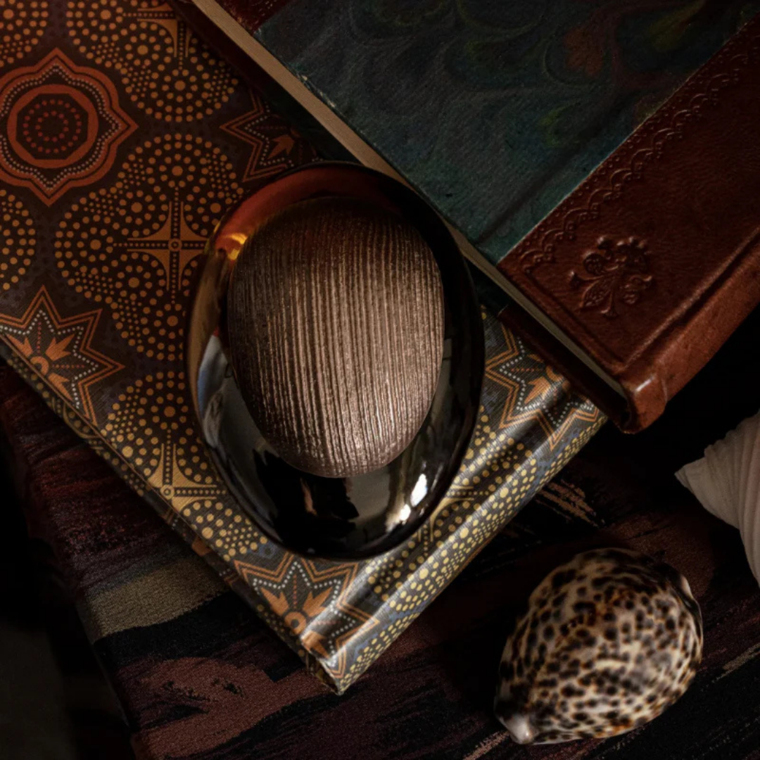 Majda Bekkali Mon Nom est Rouge Extrait de Parfum, Flakon auf kunstvollen Büchern und Stoff inszeniert, warm und orientalisch, erhältlich bei scent amor.